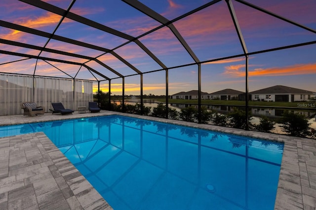 pool at dusk with a patio area and glass enclosure