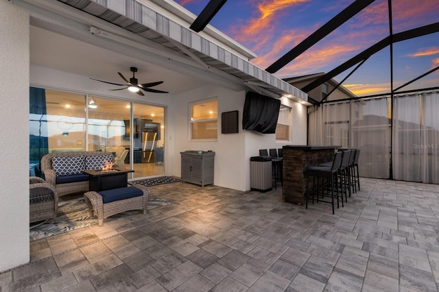 view of patio / terrace featuring exterior bar, outdoor lounge area, ceiling fan, and a lanai