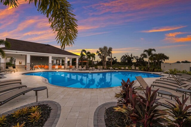 pool at dusk featuring a patio area