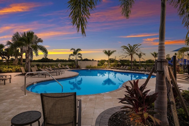 pool at dusk with a patio area