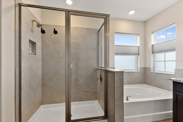 bathroom with vanity and shower with separate bathtub