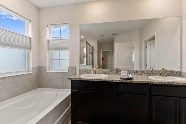 bathroom featuring independent shower and bath, dual bowl vanity, and a wealth of natural light