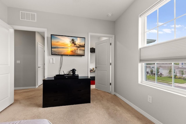 bedroom with light colored carpet and multiple windows