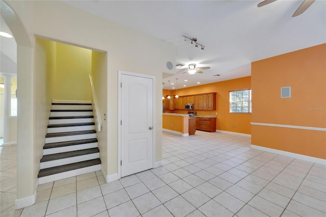 staircase with tile patterned flooring, ceiling fan, and rail lighting