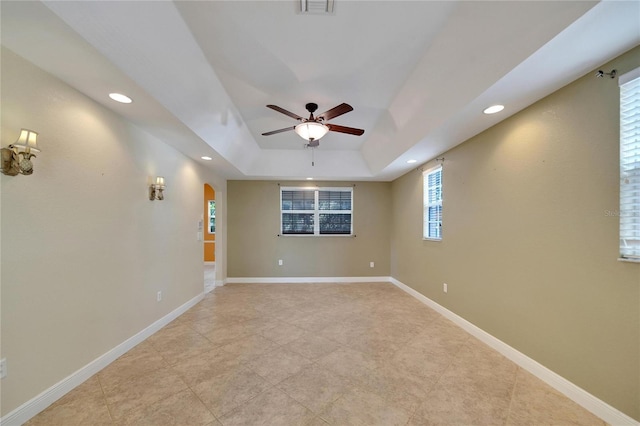 spare room featuring a tray ceiling and ceiling fan