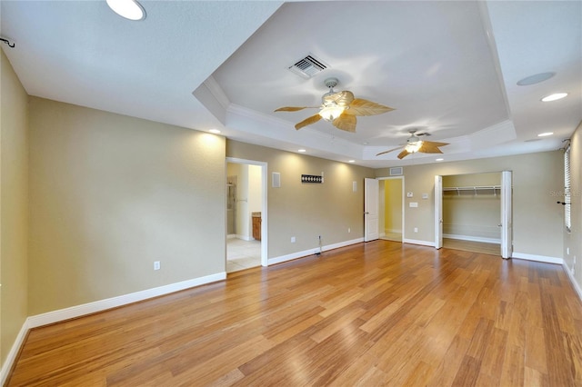 interior space featuring light hardwood / wood-style flooring, a raised ceiling, ceiling fan, and crown molding