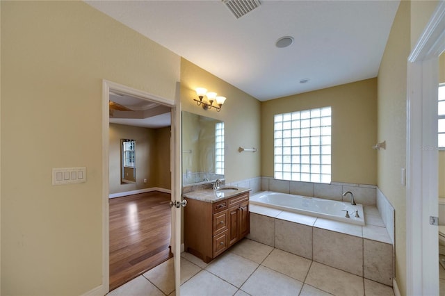 bathroom featuring tiled bath, tile patterned flooring, vanity, and toilet