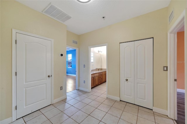 unfurnished bedroom with light tile patterned floors, ensuite bathroom, and a closet