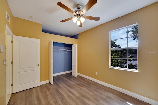 unfurnished bedroom with ceiling fan, a closet, and hardwood / wood-style floors