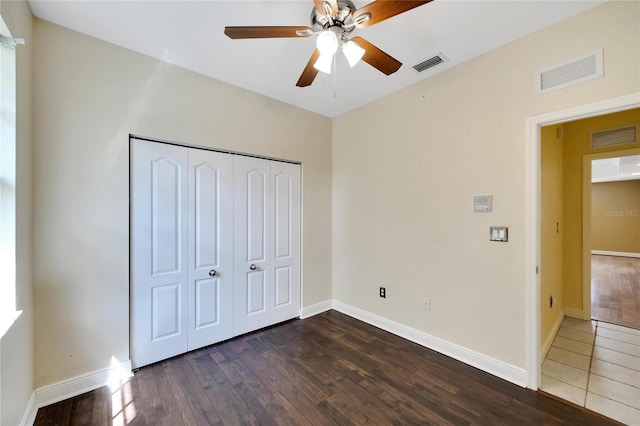 unfurnished bedroom featuring dark hardwood / wood-style flooring, ceiling fan, and a closet