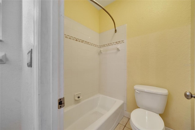 bathroom featuring toilet, tiled shower / bath combo, and tile patterned floors