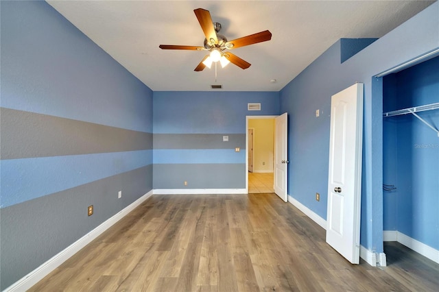 unfurnished bedroom featuring ceiling fan, a closet, and hardwood / wood-style floors