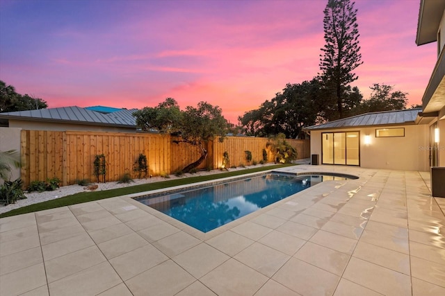 pool at dusk with a patio area, a fenced backyard, and a fenced in pool