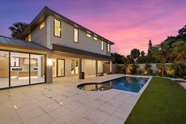 back of house featuring a patio, stucco siding, a standing seam roof, fence, and metal roof