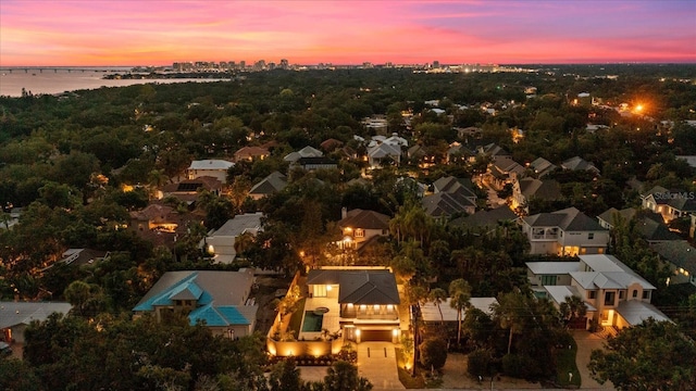 aerial view at dusk with a water view and a residential view