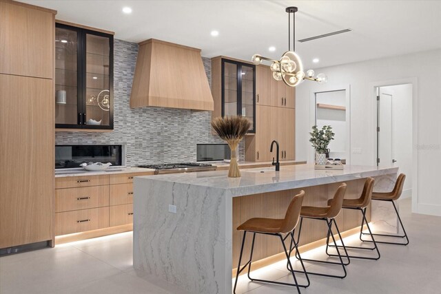 kitchen with backsplash, modern cabinets, custom exhaust hood, and pendant lighting