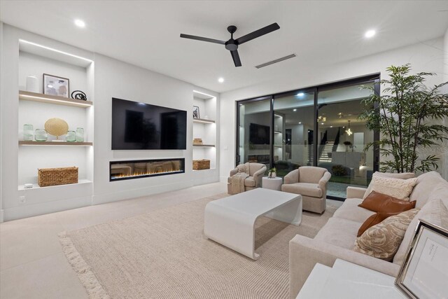 living room featuring recessed lighting, a glass covered fireplace, visible vents, and built in features