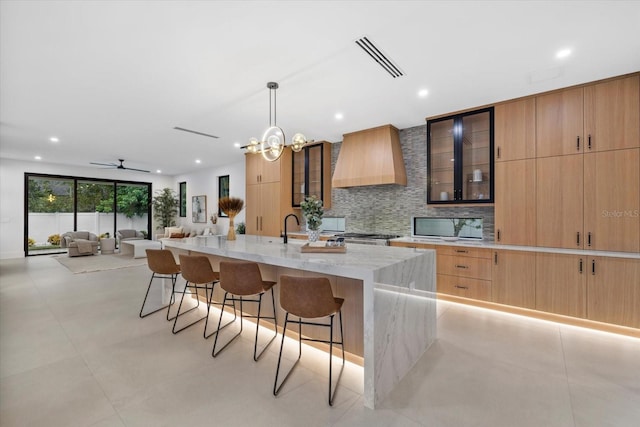 kitchen with a spacious island, visible vents, backsplash, modern cabinets, and custom range hood