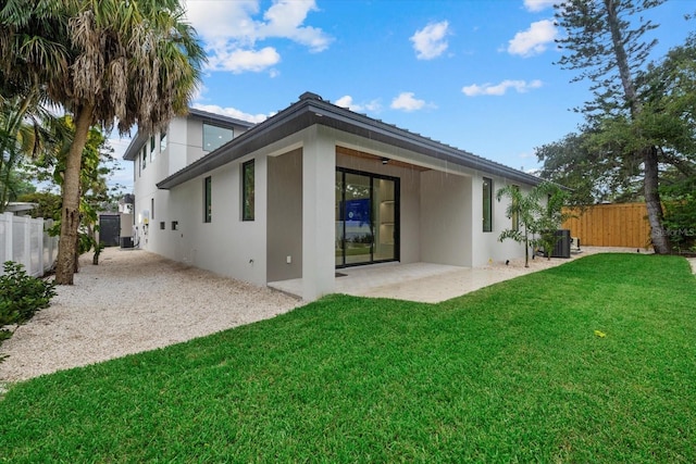 back of property with stucco siding, fence, a lawn, and a patio