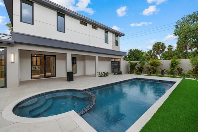 back of house featuring a patio area, a fenced backyard, a pool with connected hot tub, and stucco siding