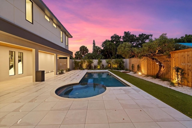 pool at dusk featuring a patio area, a fenced backyard, and a pool with connected hot tub