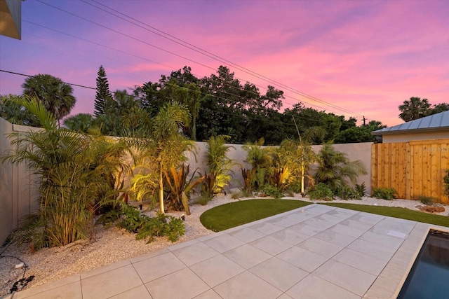 yard at dusk with a patio area and a fenced backyard