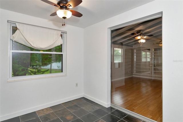 unfurnished room featuring ceiling fan and beamed ceiling