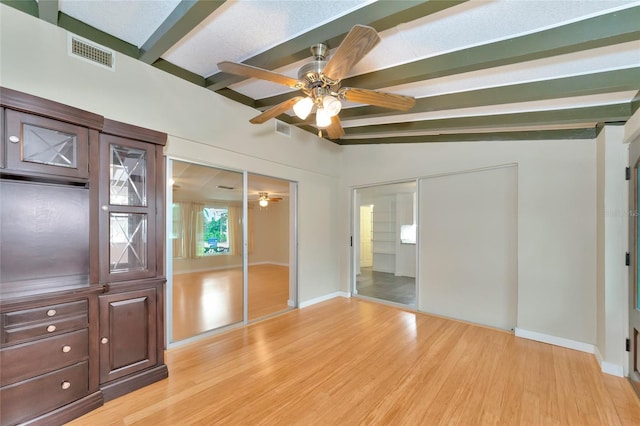 unfurnished bedroom with ceiling fan, light hardwood / wood-style floors, and vaulted ceiling with beams