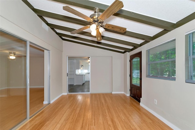 spare room with ceiling fan, light wood-type flooring, and vaulted ceiling with beams