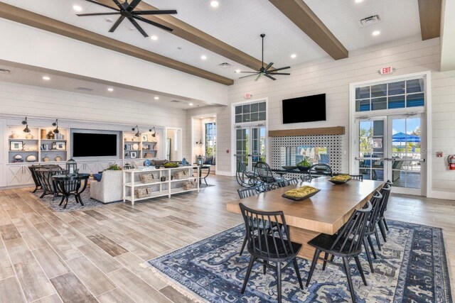 dining area featuring wood walls, ceiling fan, french doors, and beamed ceiling