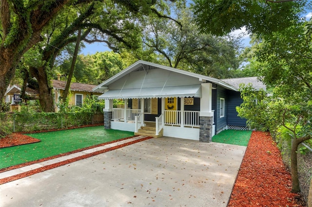 view of front of house featuring covered porch, driveway, a front yard, and fence