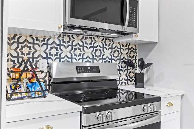 kitchen with white cabinetry, stainless steel appliances, and backsplash