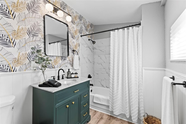 bathroom with a wainscoted wall, toilet, shower / bath combo with shower curtain, vanity, and wood finished floors