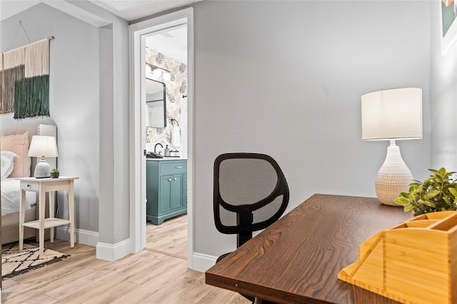 office with light wood finished floors, a sink, and baseboards