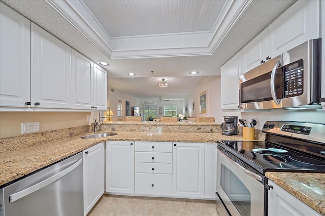 kitchen featuring stainless steel appliances, a raised ceiling, sink, and white cabinets