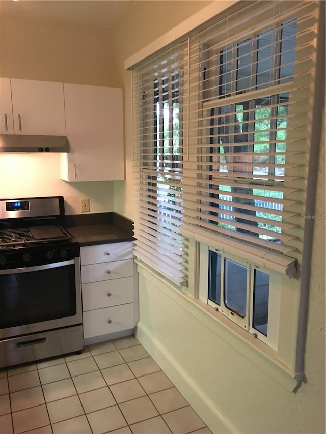 kitchen featuring stainless steel range with gas cooktop, light tile patterned flooring, a wealth of natural light, and white cabinets