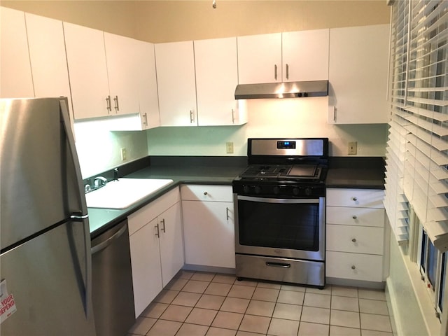 kitchen with sink, stainless steel appliances, light tile patterned floors, and white cabinetry