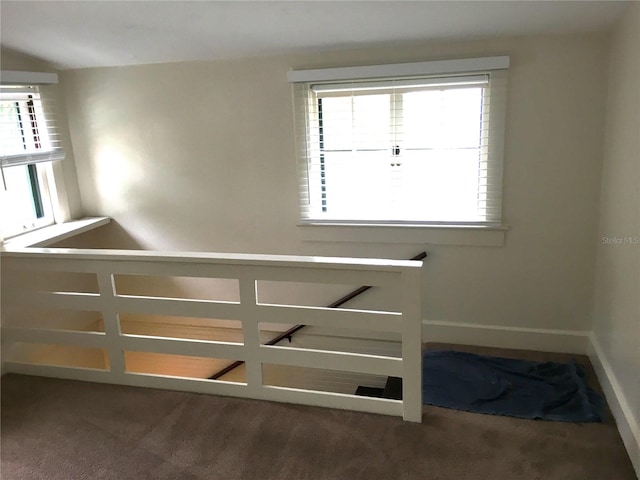 stairway with a wealth of natural light and dark carpet