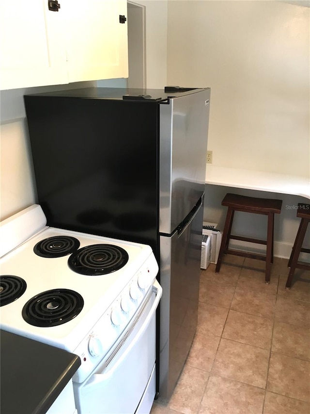 kitchen with white electric range, white cabinets, and light tile patterned floors