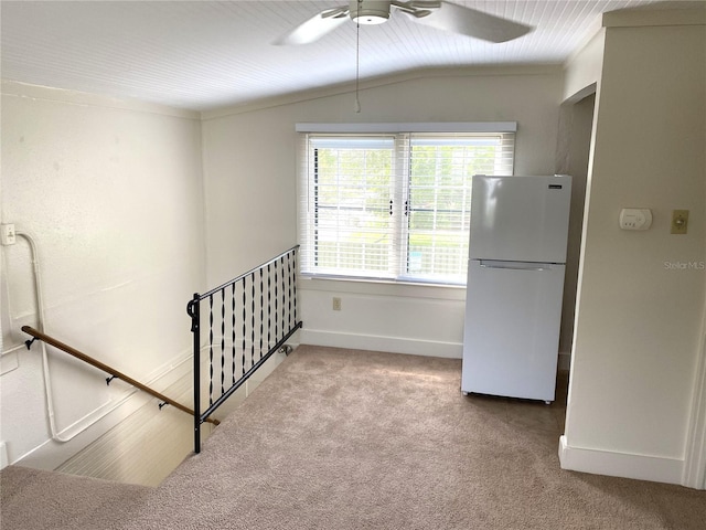 unfurnished bedroom with ceiling fan, carpet flooring, white refrigerator, and vaulted ceiling