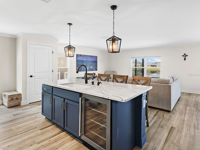 kitchen with sink, hanging light fixtures, an island with sink, and wine cooler