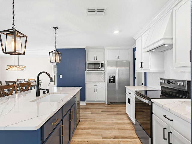 kitchen featuring appliances with stainless steel finishes, custom exhaust hood, decorative light fixtures, white cabinetry, and sink