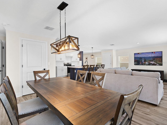 dining area featuring ornamental molding and light hardwood / wood-style flooring