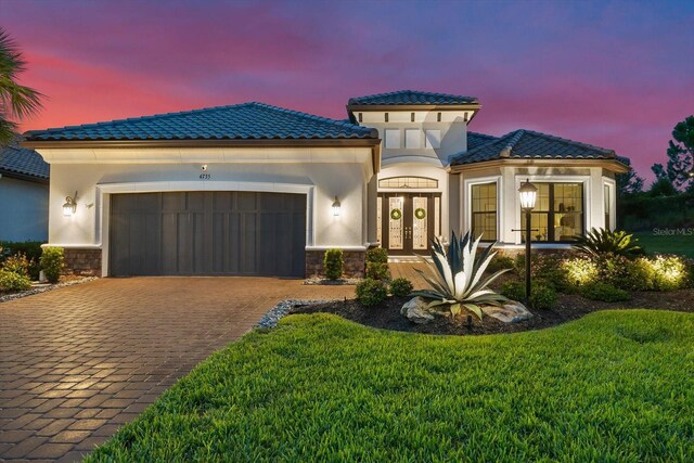 mediterranean / spanish-style home featuring a garage, french doors, and a lawn