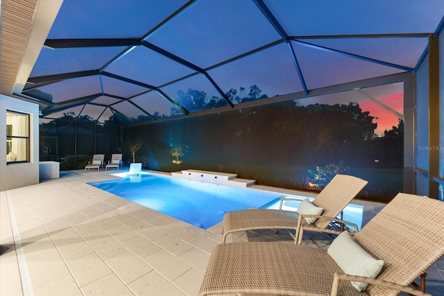 pool at dusk featuring a lanai and a patio area