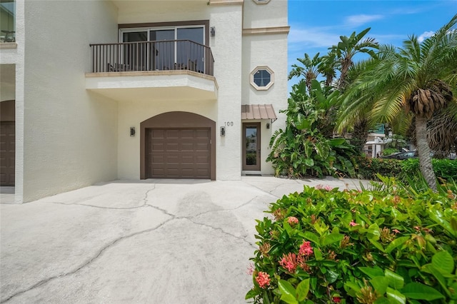 view of exterior entry with a balcony and a garage