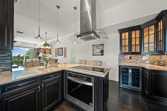 kitchen featuring tasteful backsplash, hanging light fixtures, dark hardwood / wood-style flooring, oven, and island exhaust hood