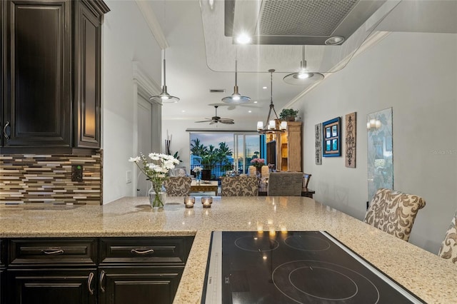 kitchen featuring stovetop, light stone counters, pendant lighting, ceiling fan, and ornamental molding