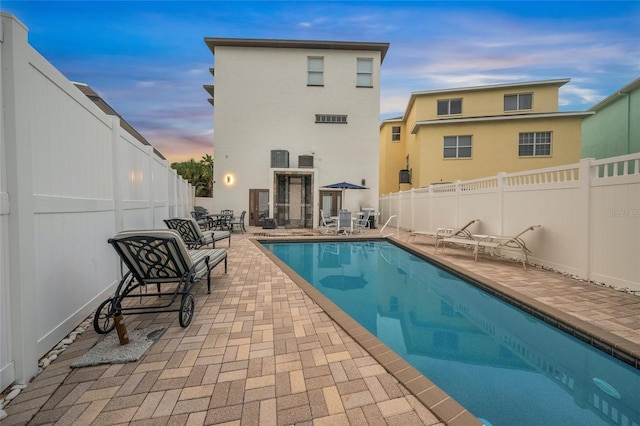 pool at dusk with a patio area