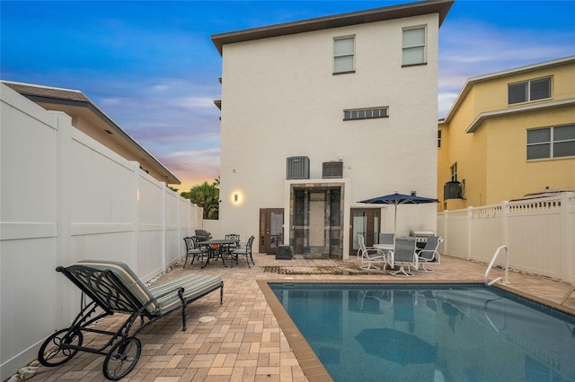 back house at dusk with a patio area and a fenced in pool